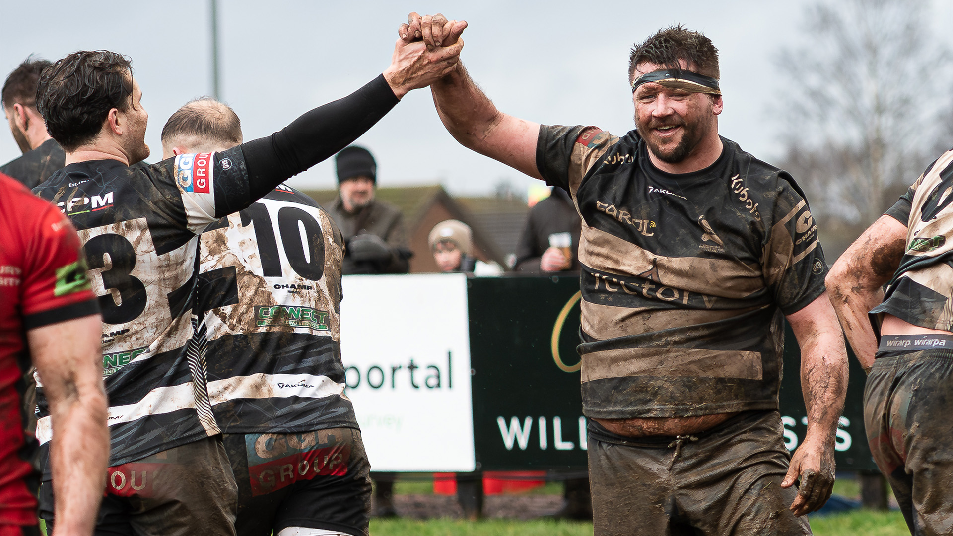 Alun Walker high fives a teammate while covered in mud