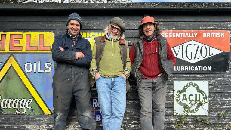 Allen Millyard, Henry Cole and Guy ‘Skid’ Willison stand in front of a shed with old garage signs hanging on it