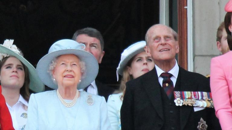 Queen Elizabeth II and Prince Philip looking to the sky from the Buckingham Palace balcony