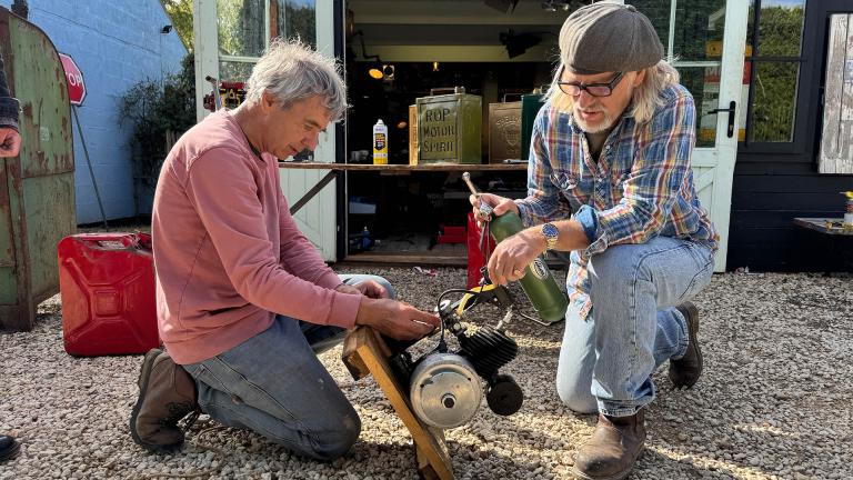 Henry Cole and Allen Millyard inspect an old motor in front of a shed