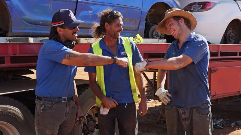 Outback Wreckers crew smile and fist bump each other