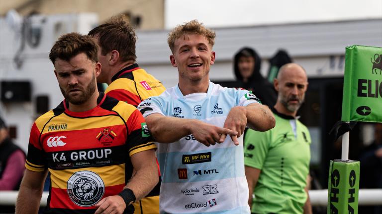 A Rotherham player celebrates scoring a try by making an 'A' symbol with his fingers to the camera